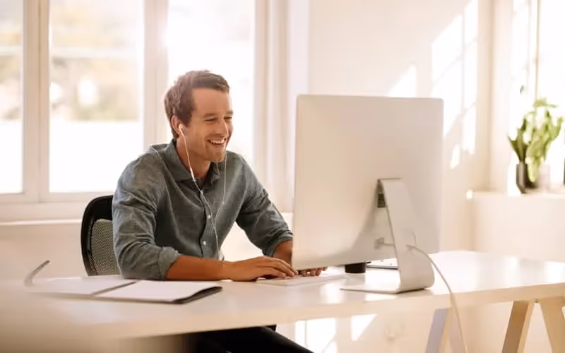auto entrepreneur face à son ordinateur et portant des écouteurs en visio dans son bureau