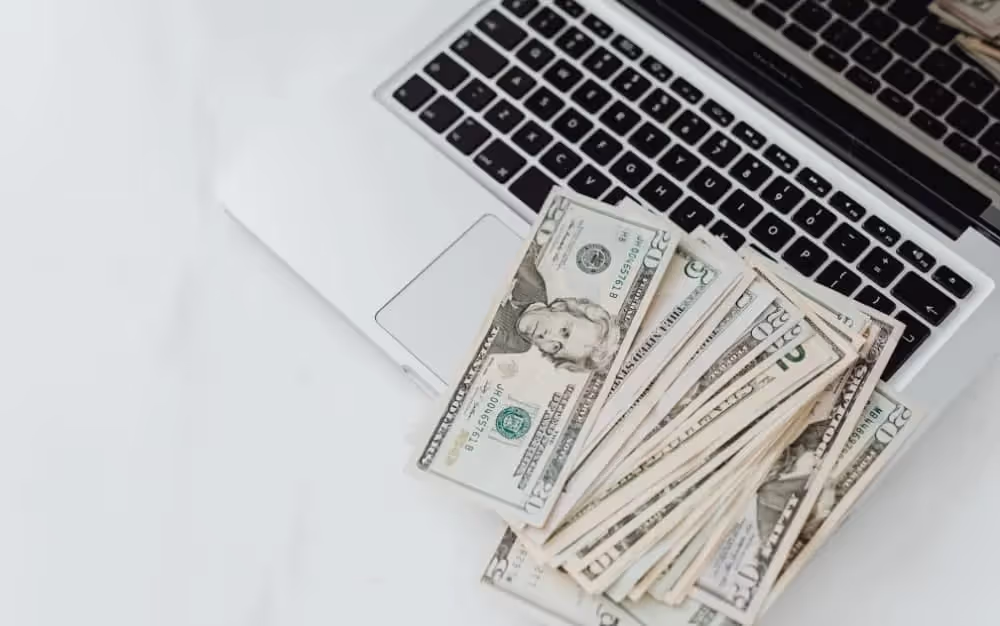Liasse de billets posée sur un ordinateur portable