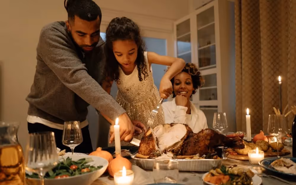 Père qui coupe la dinde avec sa famille à table durant thanksgiving