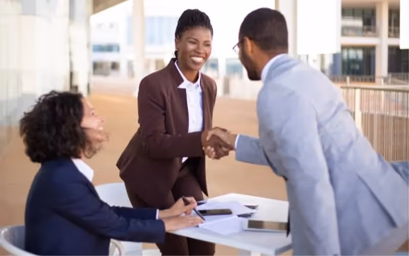 Deux femmes accueillent dans leur bureau un client masculin