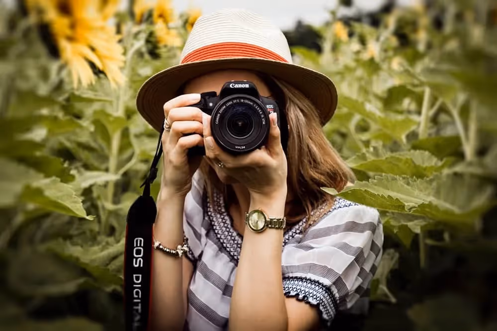 Femme qui apprend la photographie en anglais en prenant une photo dans la nature à l'aide de son appareil photo
