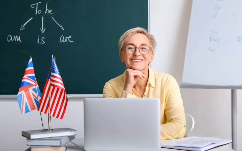 Professeure d'anglais souriante face à son ordinateur en classe organisant un cours d'anglais individuel