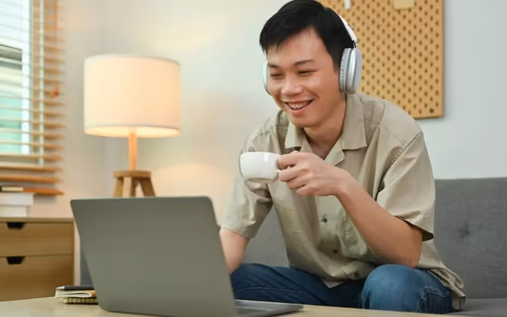 Jeune homme effectuant un cours d'anglais individuel dans son salon en visio