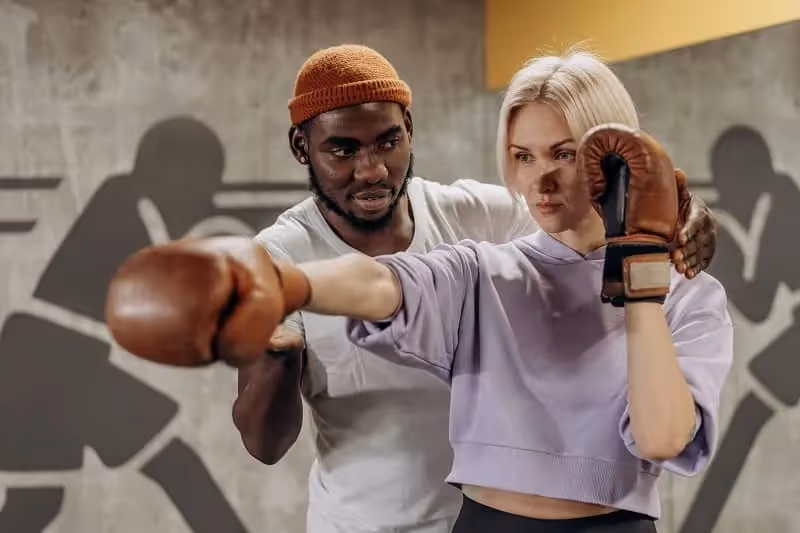 Femme blonde concentrée qui apprends une prise de boxe avec son coach
