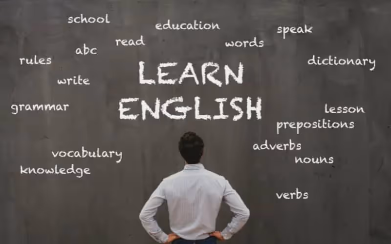 Homme devant tableau sur lequel il est écrit learn english