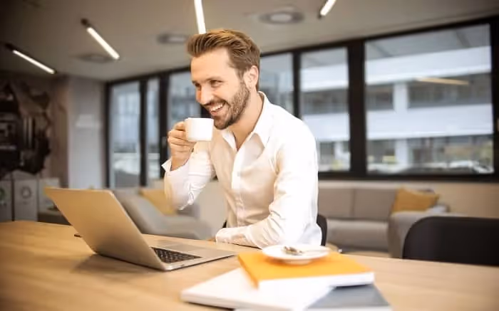 homme qui prend son café en travaillant au bureau