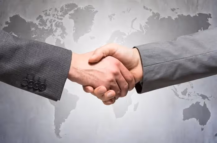 deux main qui se serrent avec carte internationale en fond