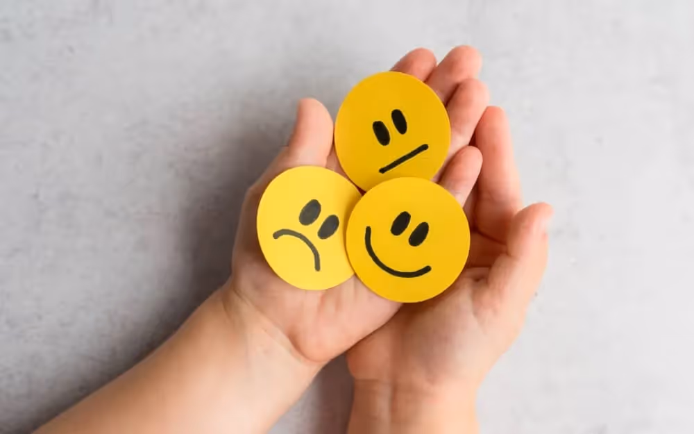 Emojis jaunes posés sur les paumes de main d'une personne, les emojis sont les émotions que peuvent ressentir les personnes quand on décrit une image en anglais