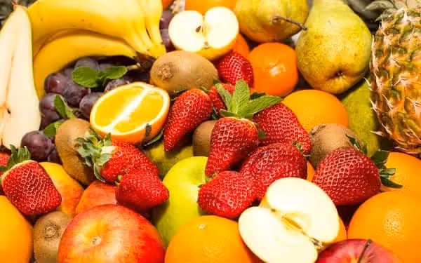 mélange de fruits dont des oranges, pommes, fraises, banane, ananas...