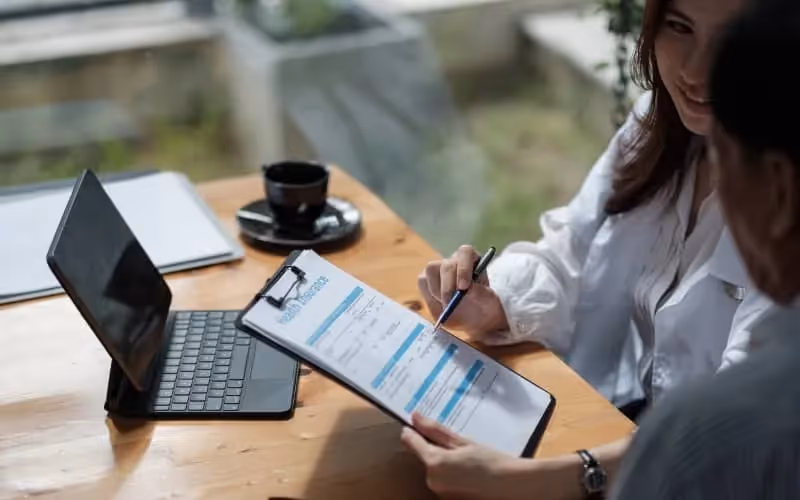 Femme qui explique l'assurance à un homme et qui lui tend un formulaire pour qu'il souscrive à une assurance en anglais