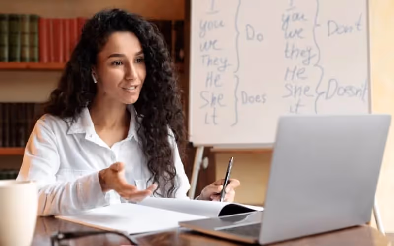 Jeune professeur d'anglais aux cheveux bouclés enseigne un cours d'anglais en visio