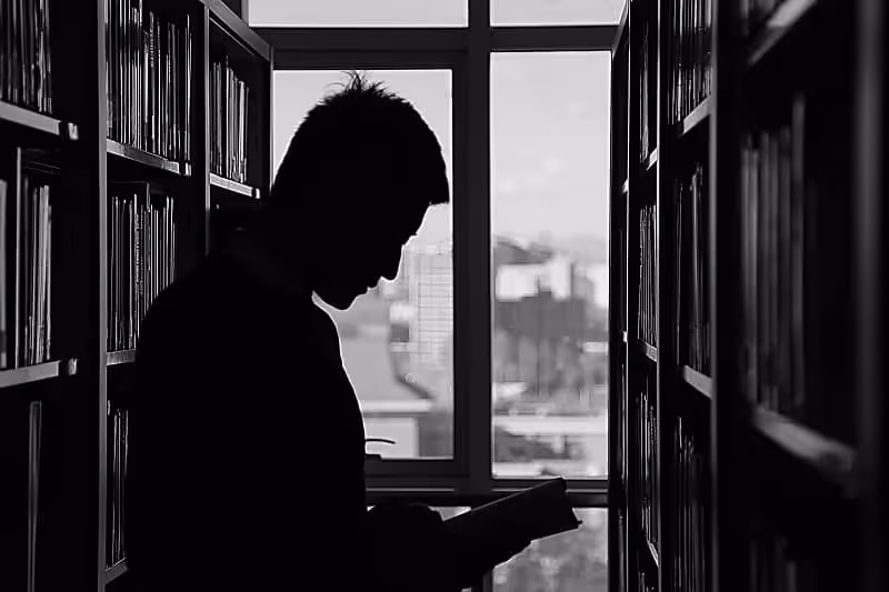 image noir et blanc d'un homme debout dans une bibliothèque