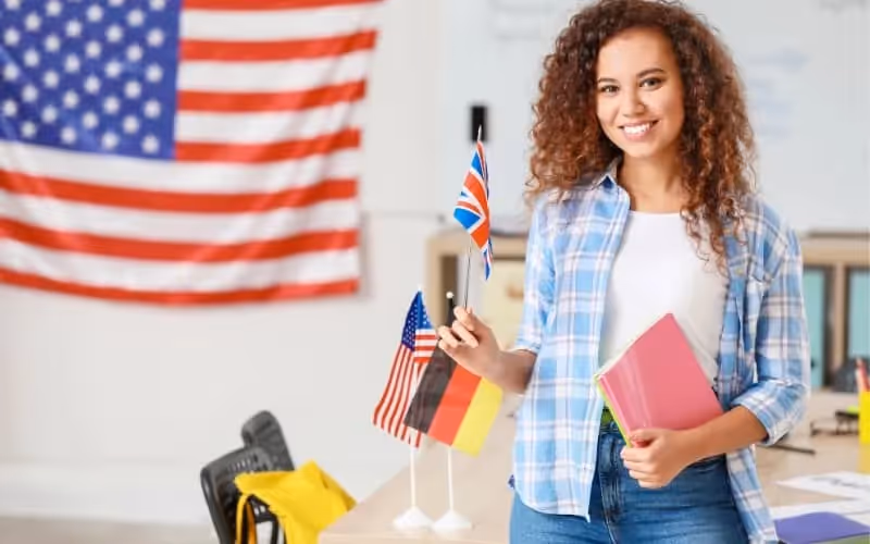 Professeur d'anglais avec en fond un drapeau américain accroché au mur