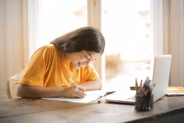femme vêtue d'un t-shirt jaune qui étudie face à son ordinateur