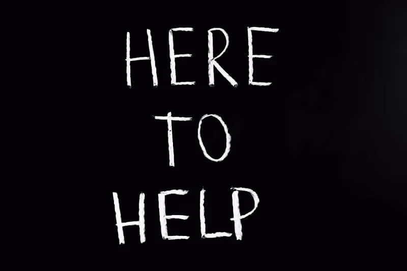 tableau noir avec écrit "here to help"