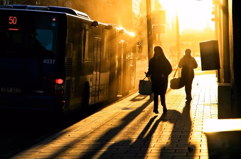 Image d'une femme qui marche à côté d'un bus à l'arrêt pour illustrer l'article sur comment prendre le bus en anglais facilement