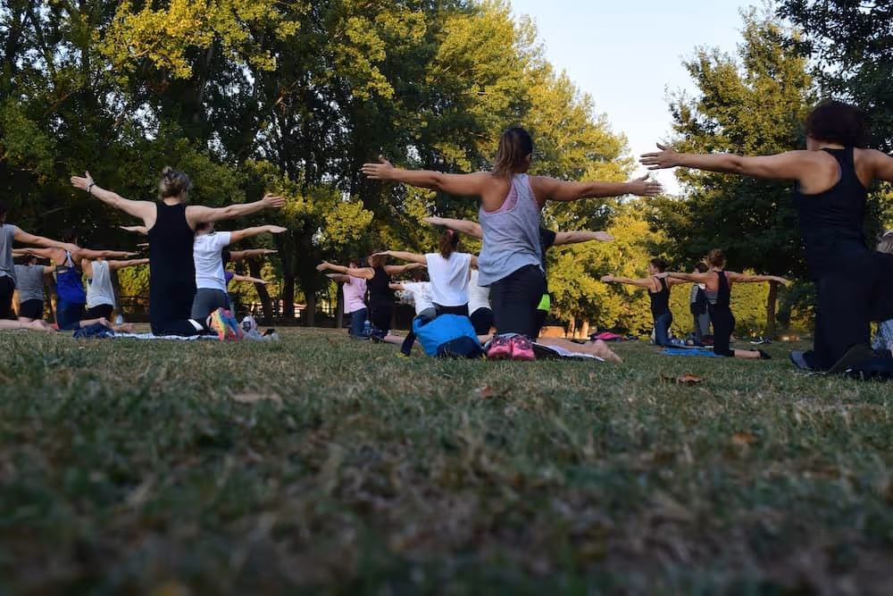 Image d'un groupe de personne dans un parc qui effectue un cours de yoga en anglais