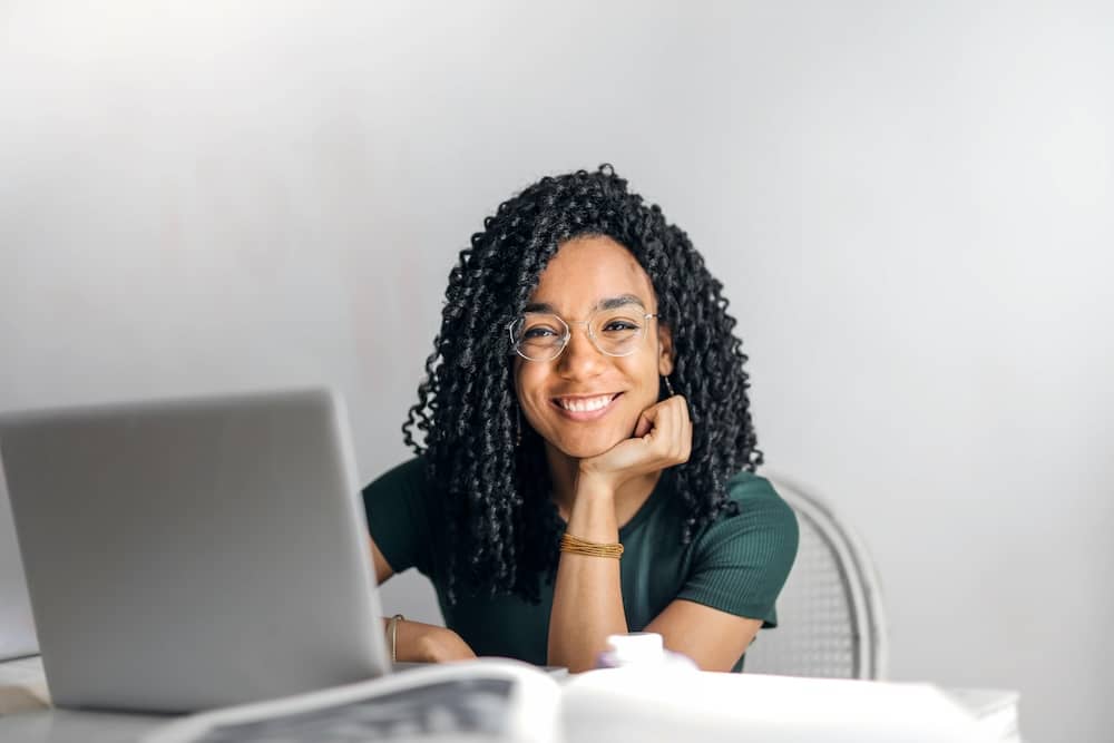 Jeune femme qui sourit face à son ordinateur pour illustrer l'article sur la certification B1 anglais