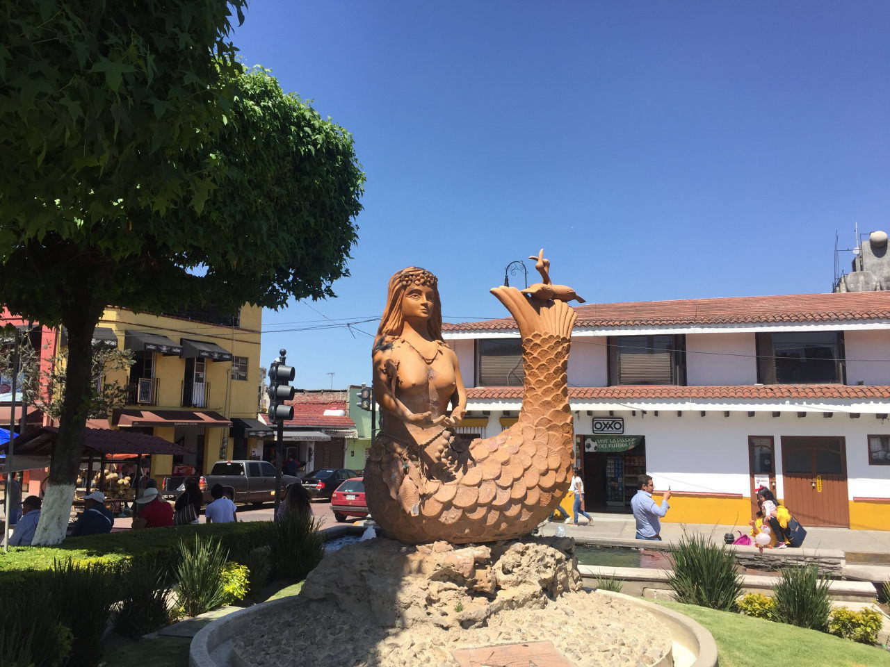 Une statue d'une sirène debout au milieu d'une fontaine par une journée ensoleillée, comme le regard des touristes.