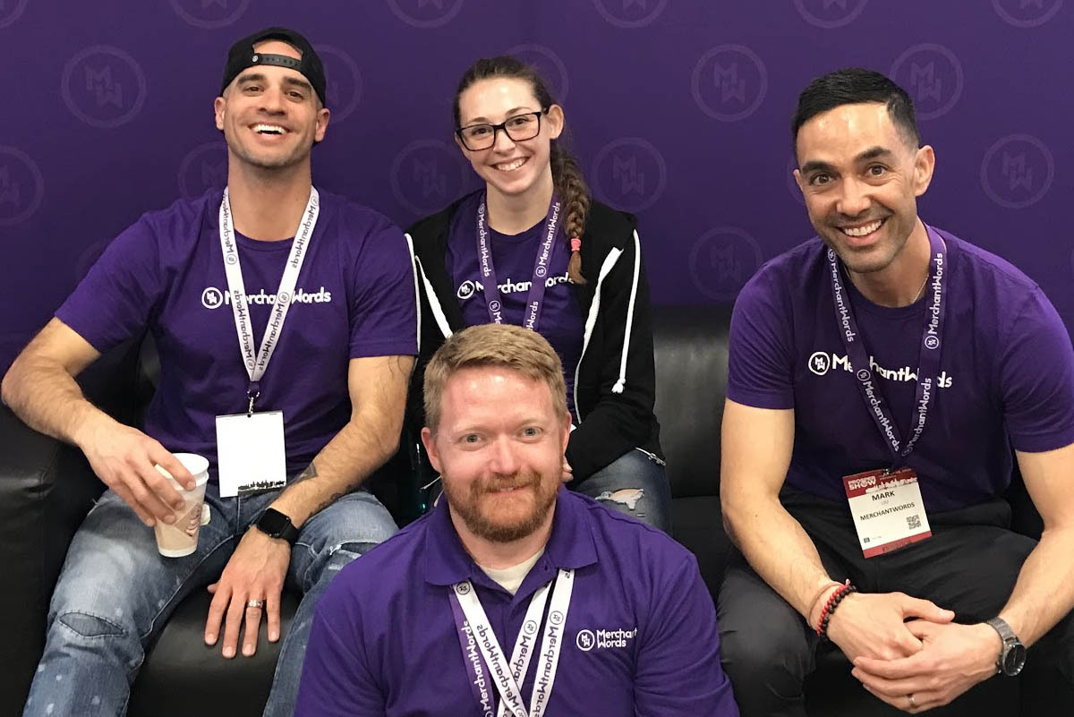 MerchantWords and Power Listing team members sitting on a black couch in their tradeshow booth 