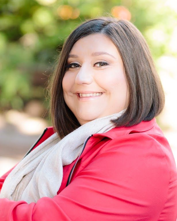 Smiling woman with brown hair wearing red jacket and gray scarf