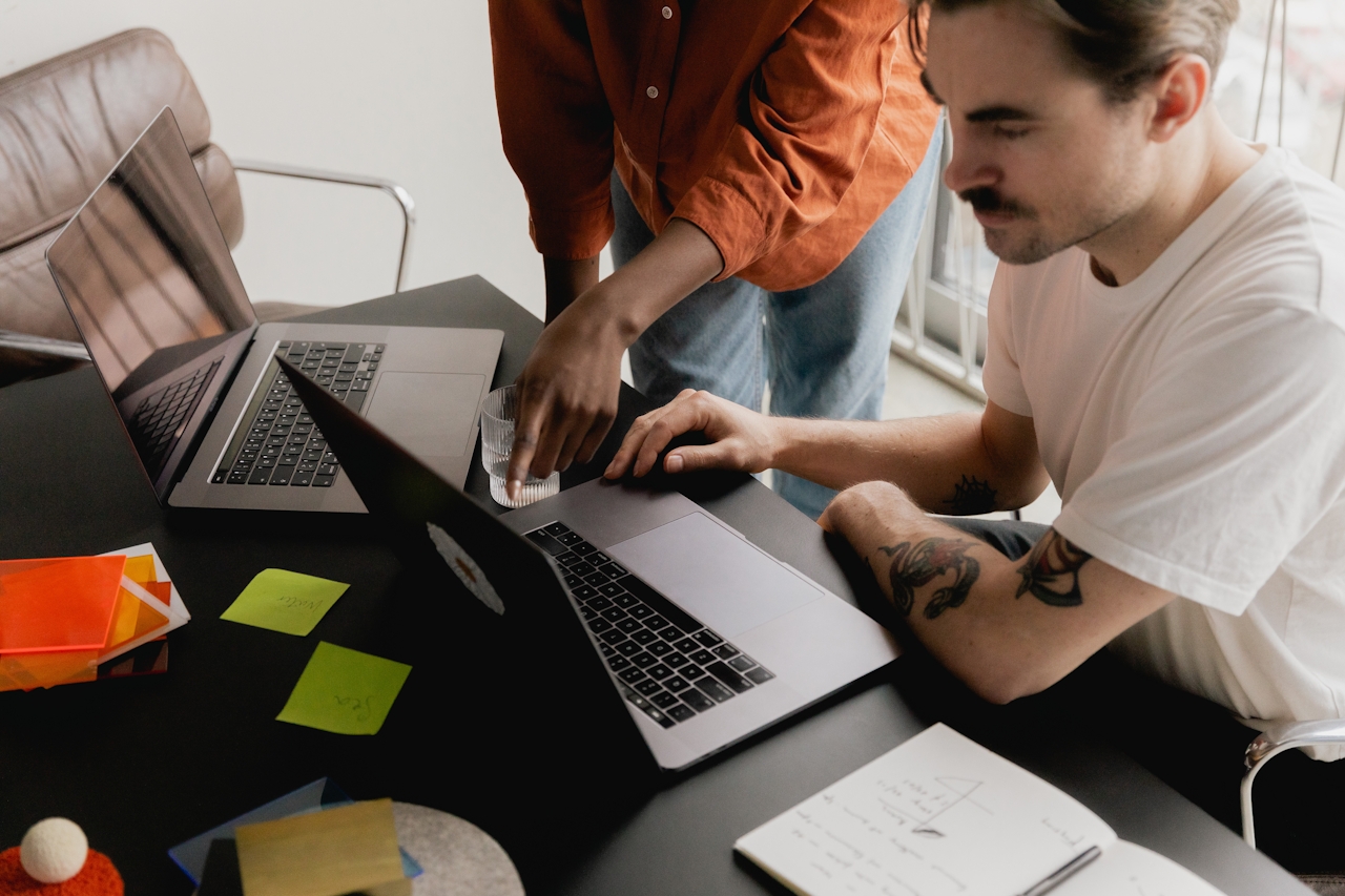 two people working at a desk with their computers - Spay Marketing