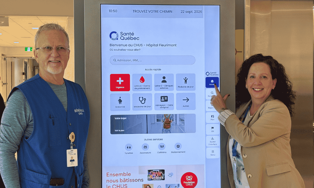Mario Boutin, bénévole, et Nadia Mathieu, adjointe au directeur de la Direction des services techniques (DST), devant la borne d’orientation numérique de l’Hôpital Fleurimont