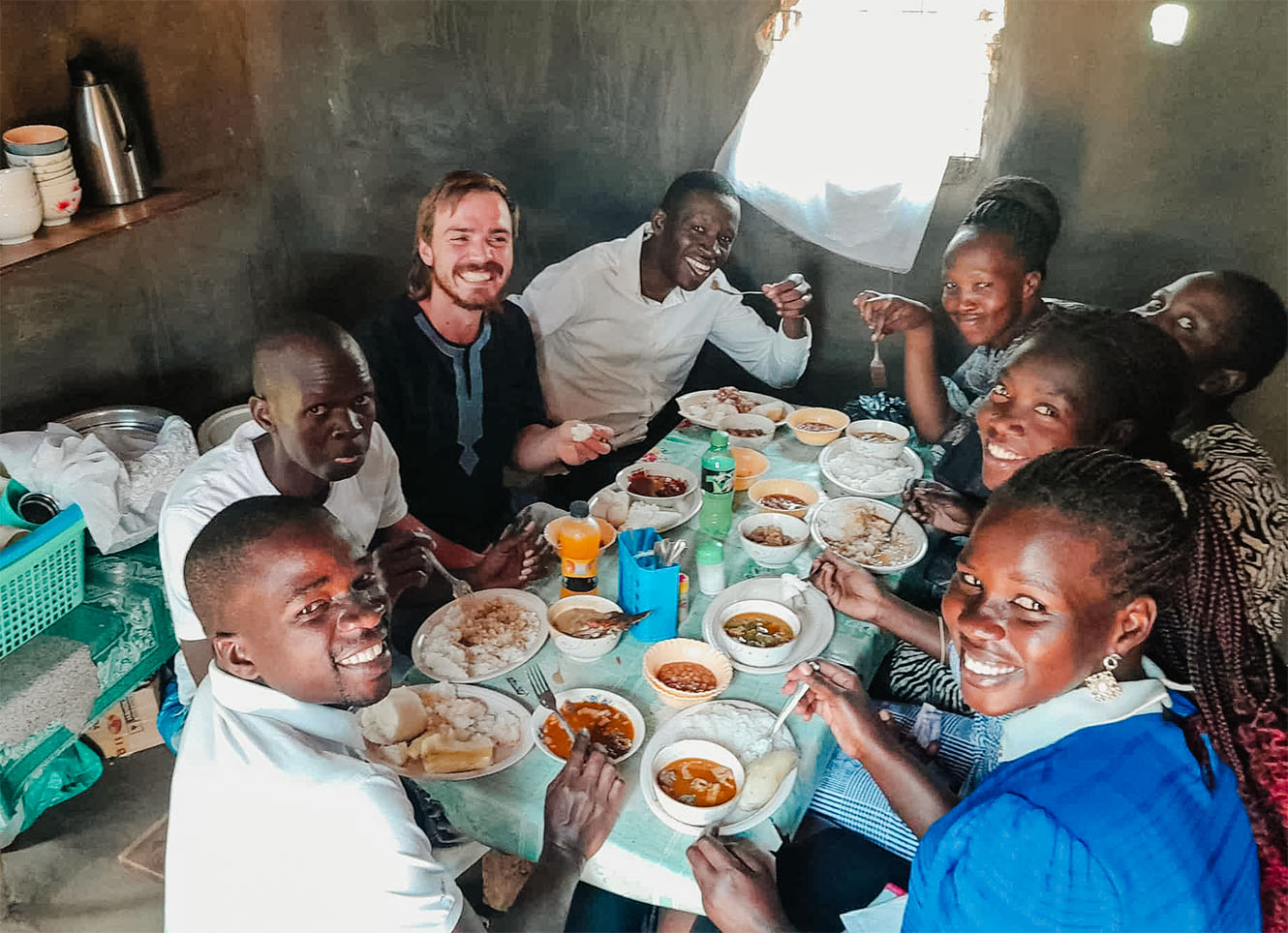 Mike Jessop eating at a table with Ugandan people