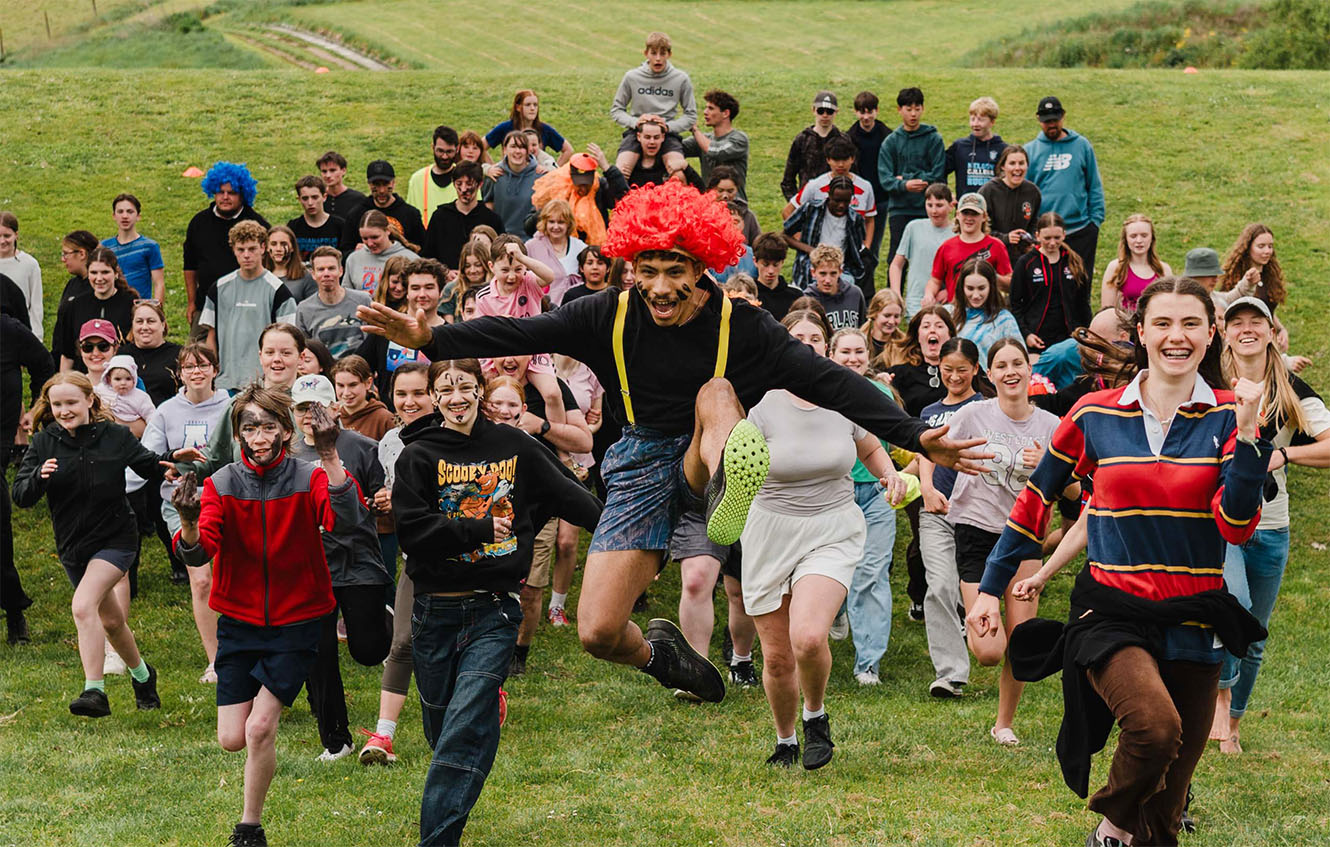 young people running towards the camera on a grassy hill