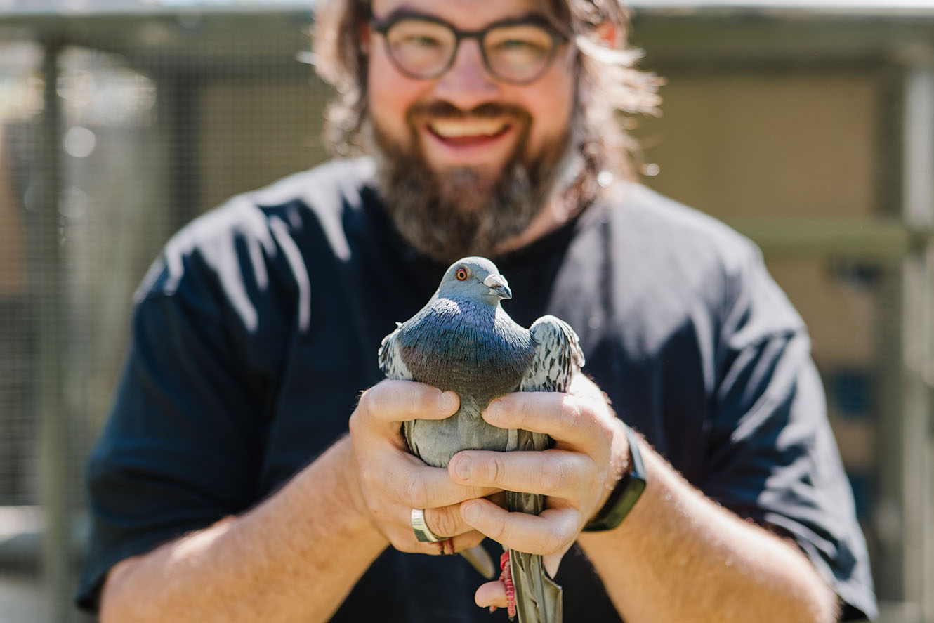 Smiling Rev Spanky Moore holds a pigeon in his hands