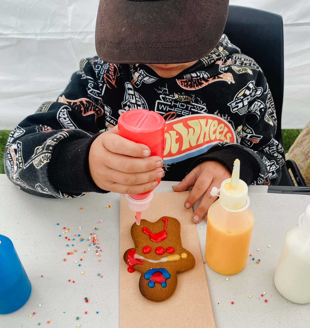 a boy decorates a gingerbread man with colourful icing