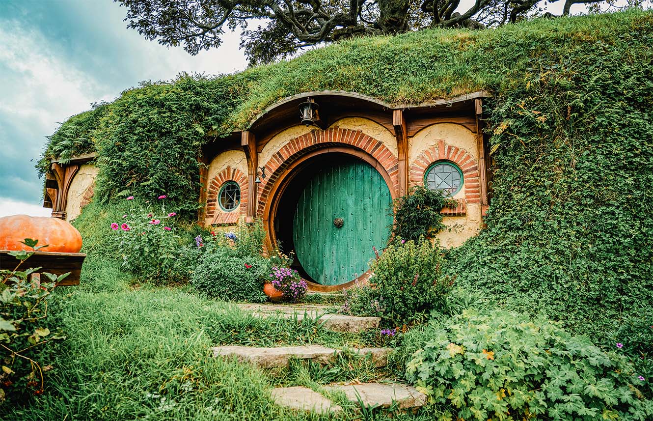 The entrance to a hobbit house with a round, green door