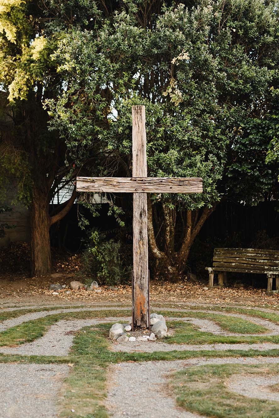 A wooden cross and gravel labyrinth outside at St Thomas in Motueka