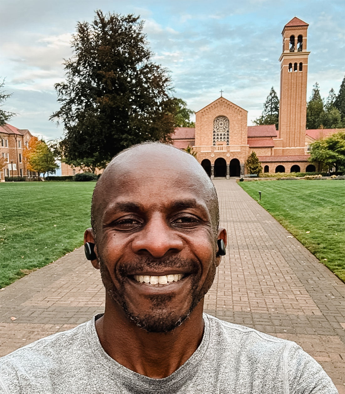 Bishop Steve Maina in front of Mount Angel Abbey with a view of the belltower behind him