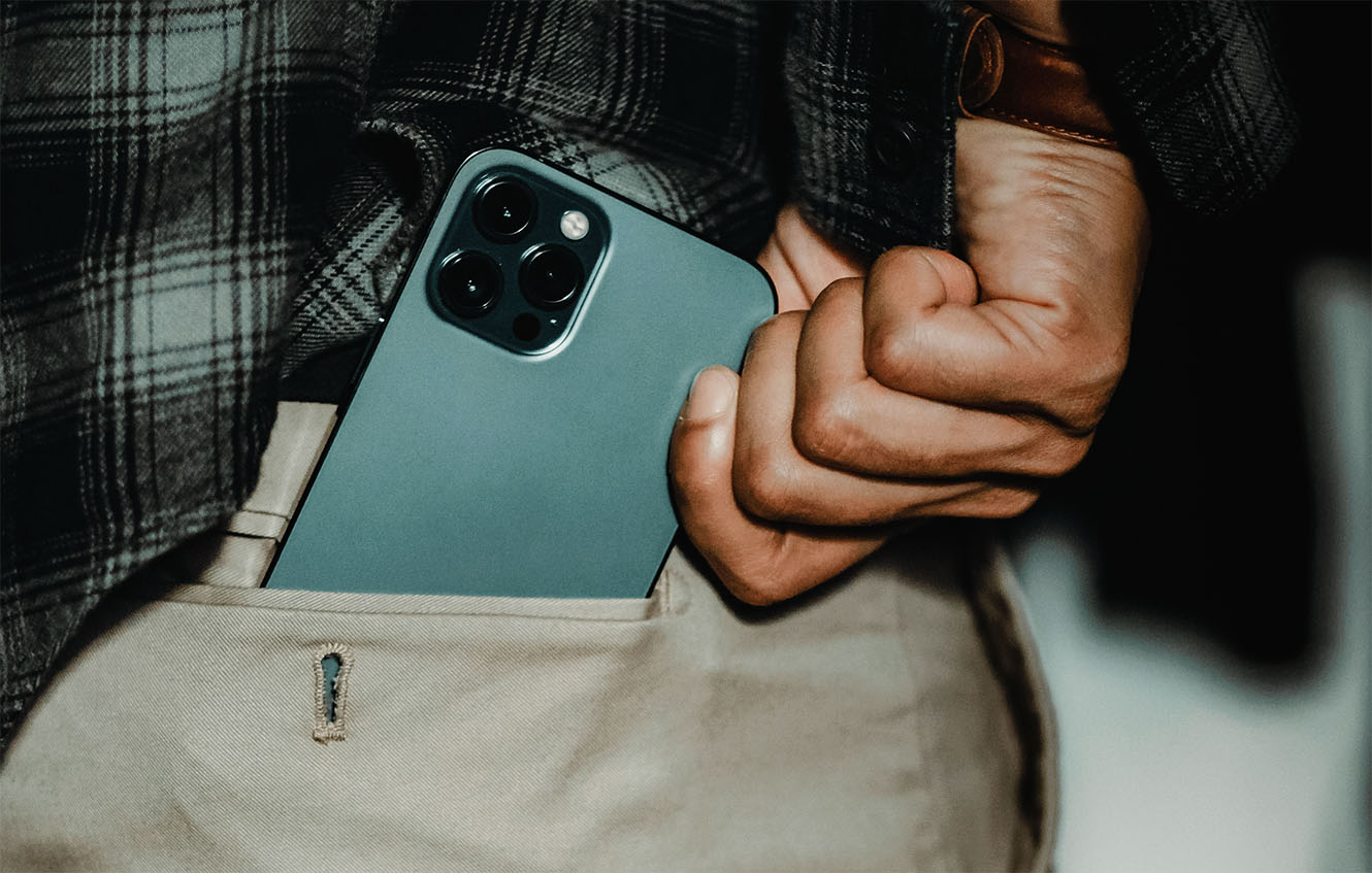 A hand pulling a smartphone out of a pants pocket
