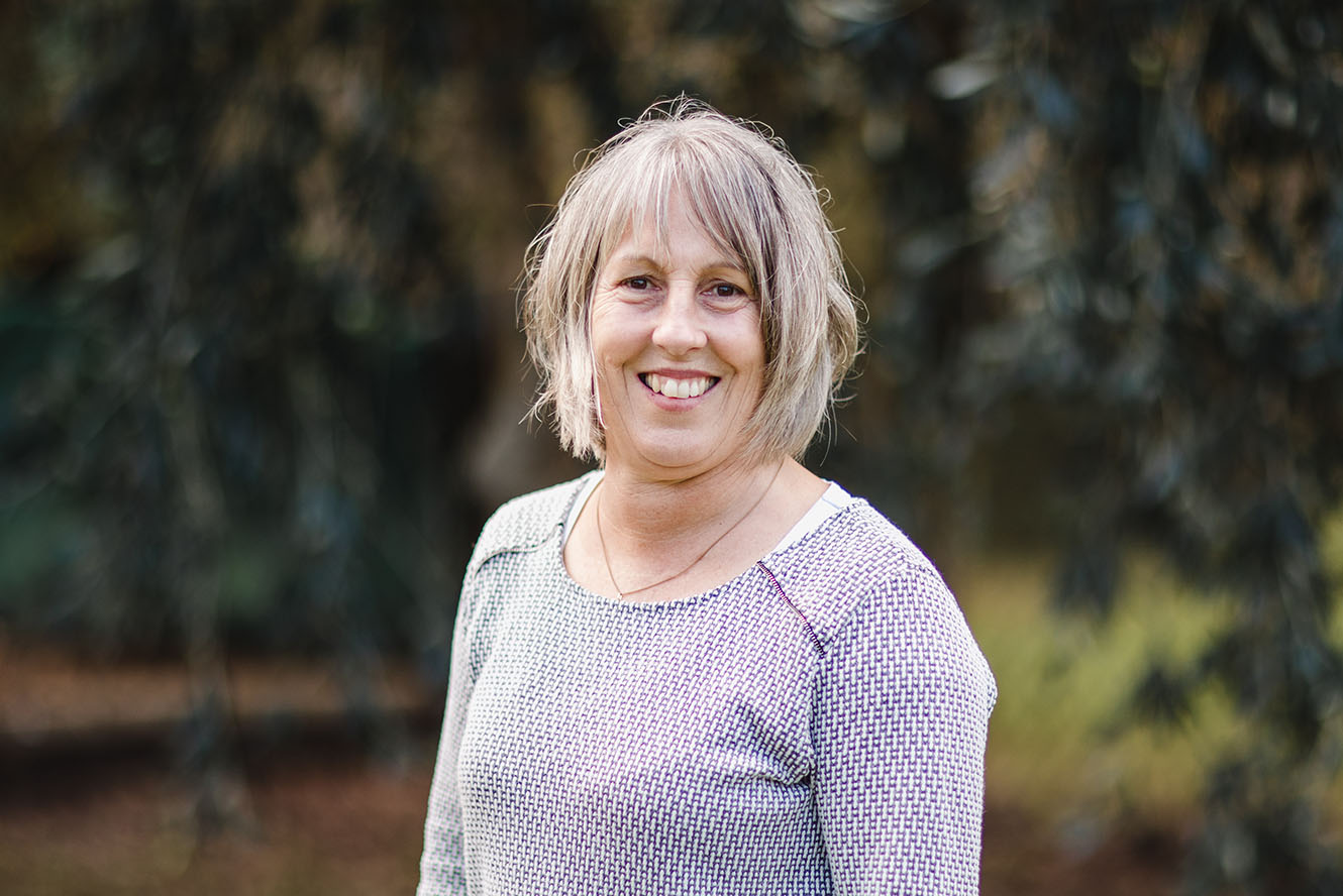 A headshot of Nicola Berthelsen in front of some outdoor foliage.