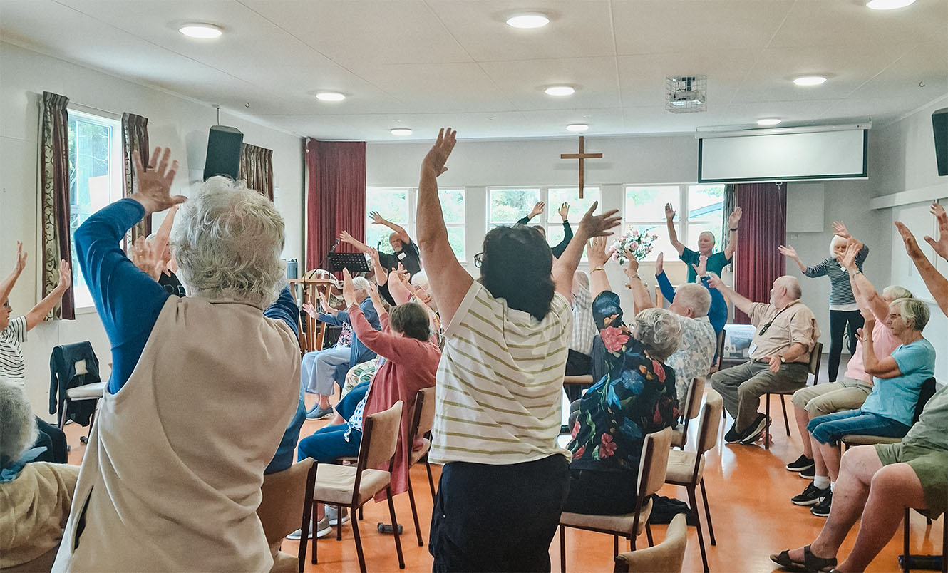Older persons with arms raised in an exercise programme at Waimea Parish.B