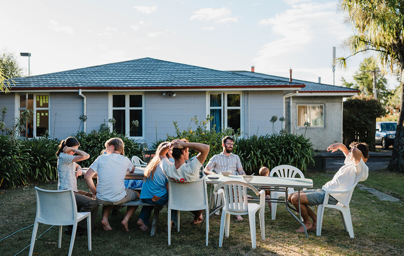 Members of the St Barnabas flat with guests having dinner outside the house