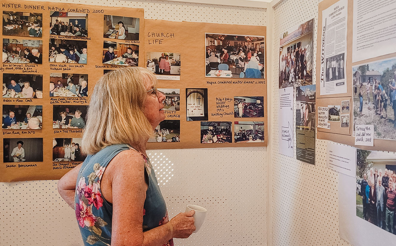 A woman reads a wall of information and historical photos.