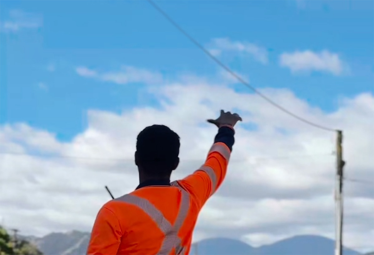 A man in high-vis vest gives a mana wave.