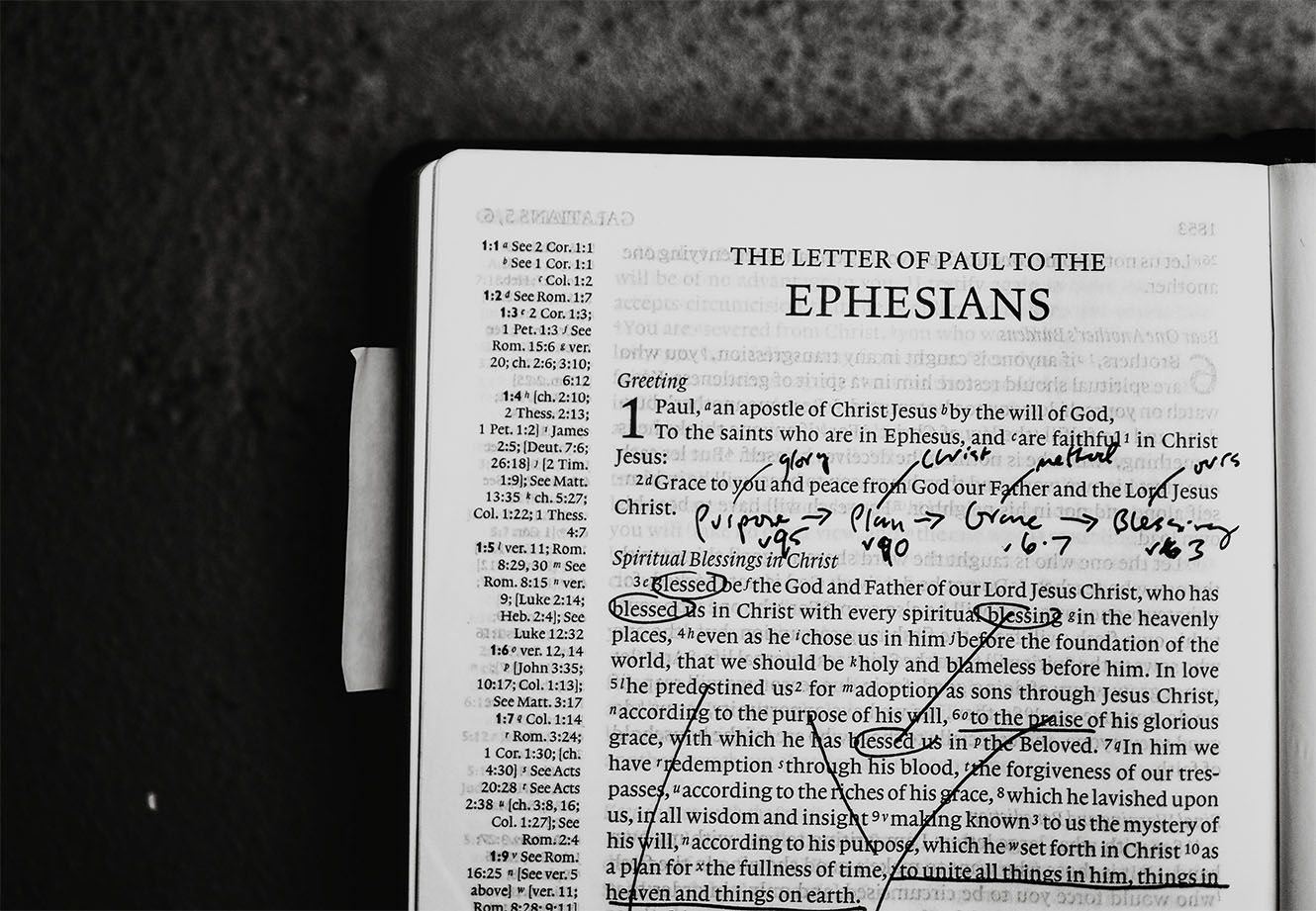 a Bible open to Ephesians filled with handwritten study notes