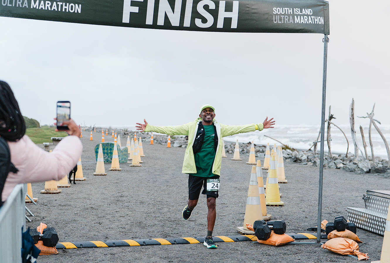 Bishop Steve Maina crosses the South Island Ultra finish line on the Hokitika coastline