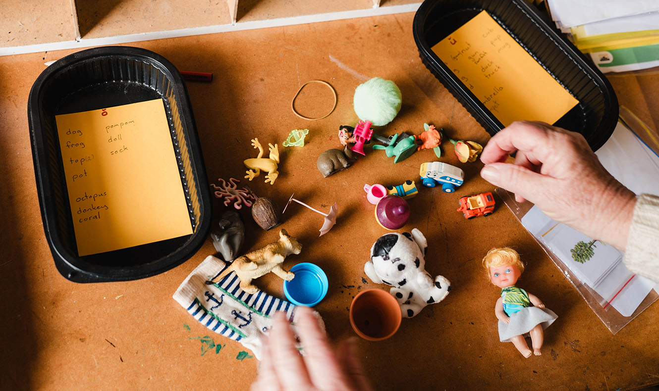 Containers filled with small items grouped by vowel sounds, which would be tipped out and mixed up for children to sort