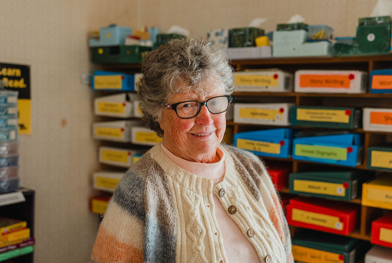 Carol Duffy smiling in front of shelves of literacy resources