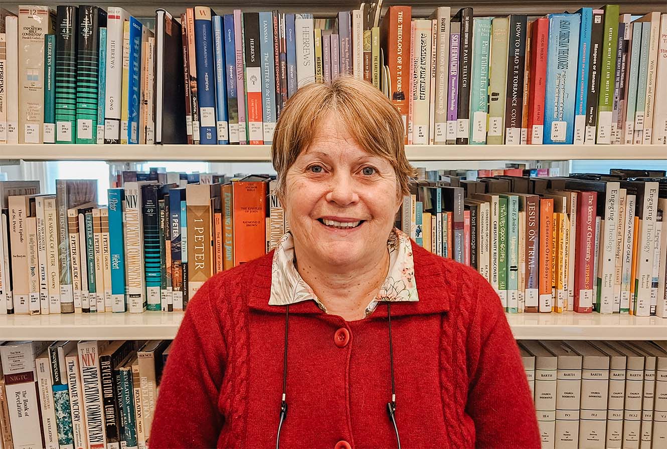 Jennifer Patterson in front of a shelf packed with theological books