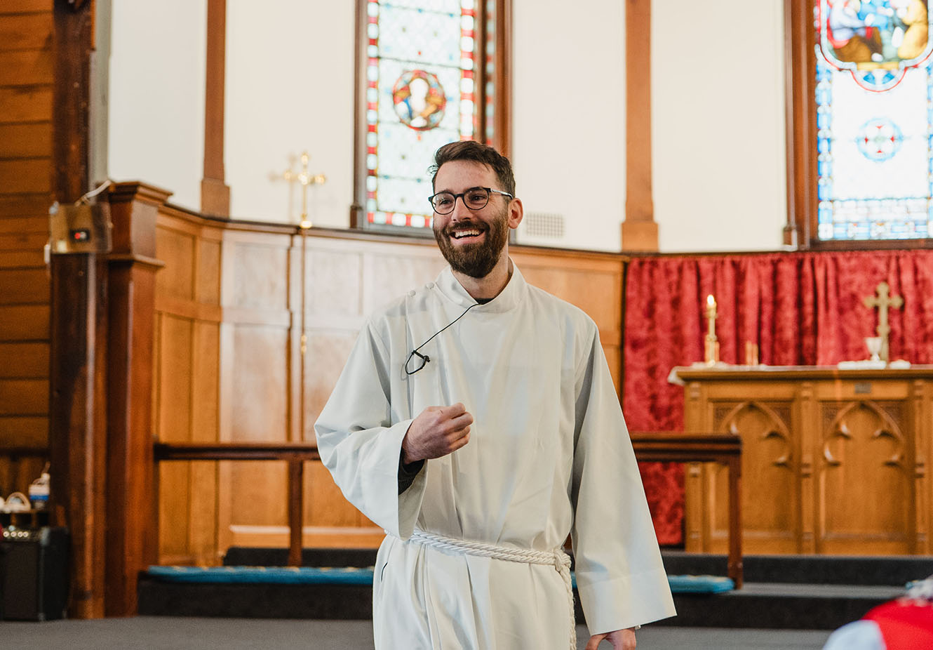 Sam Oomen in clerical robes at All Saints, grinning