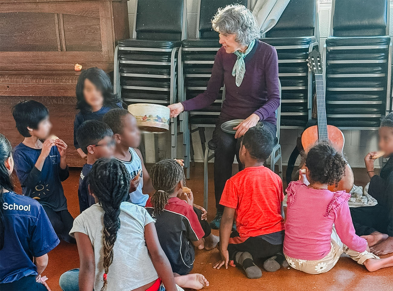 Maria hands out homemade biscuits to a group of children