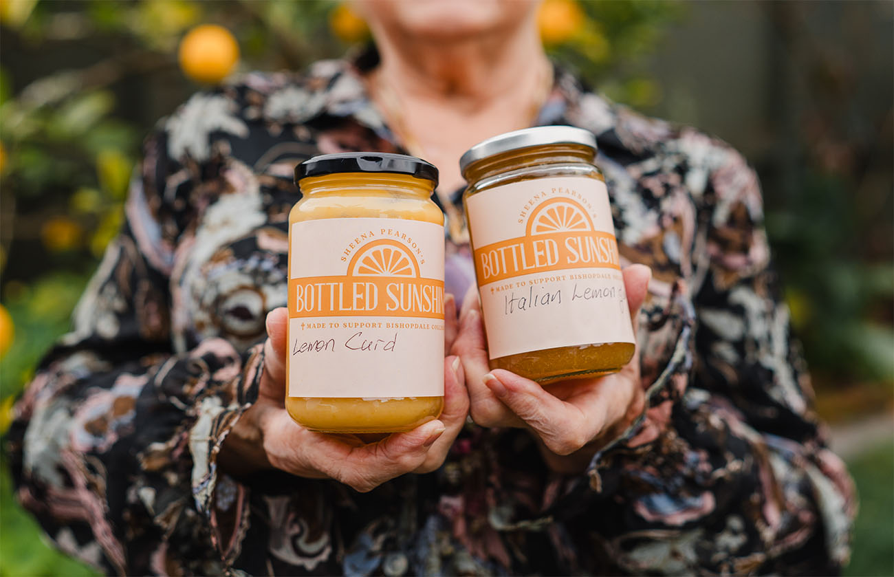 A close up of a jar of lemon curd and a jar of Italian lemon jam held by Sheena