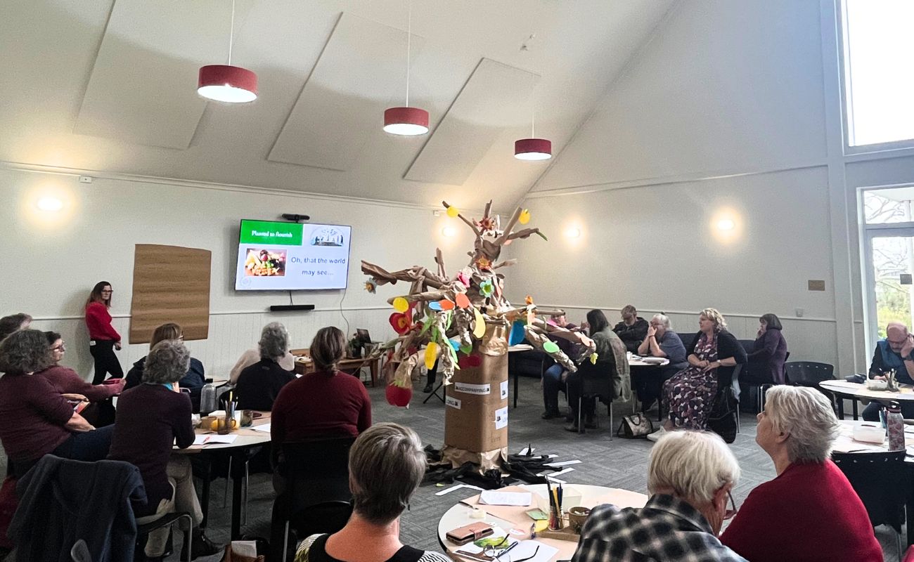 a room of people with a decorated handmade tree in the centre