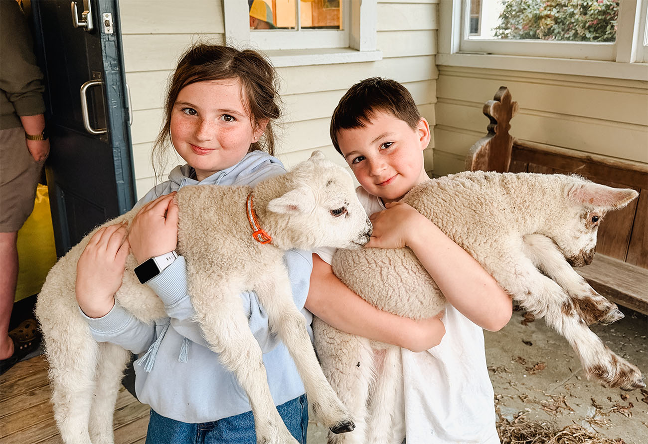 two children hold a lamb each